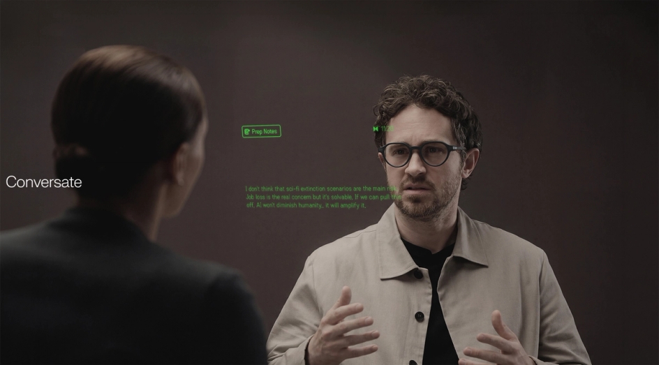 A man wearing Even G2 glasses in conversation, with green Conversate prep notes and live text floating in his field of view