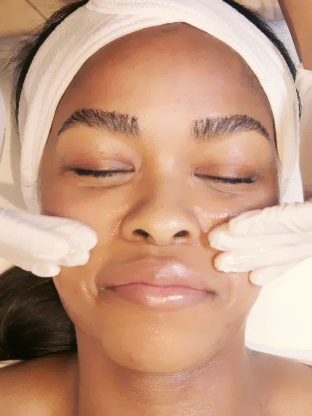 Gloved hands preparing a client's face in an Ever/Body treatment photograph