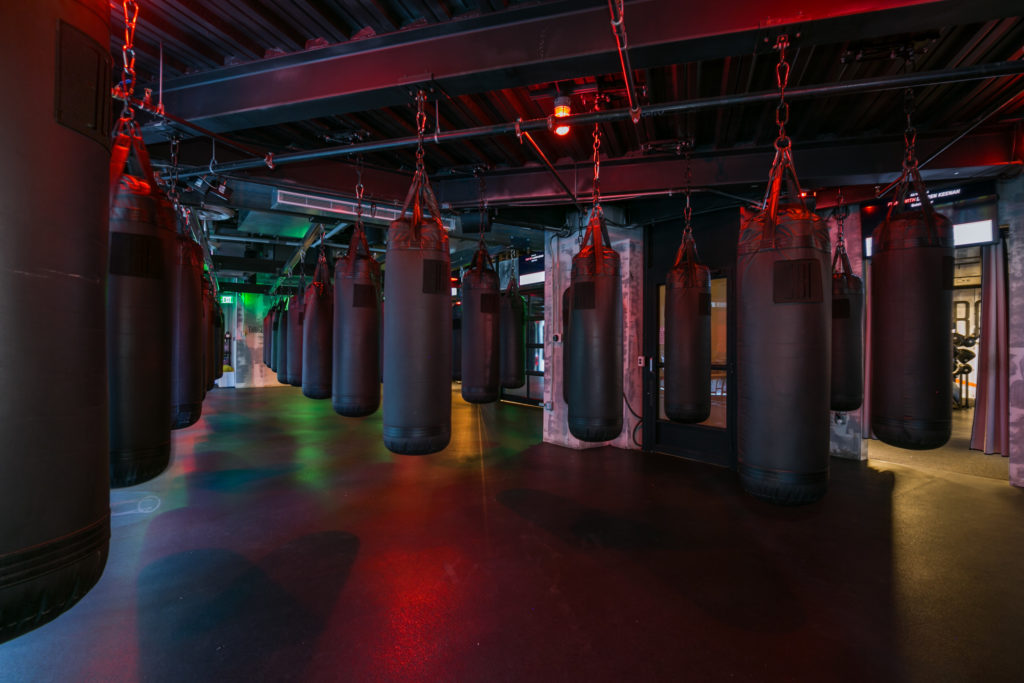 Rows of heavy bags in a red-lit EverybodyFights boxing studio