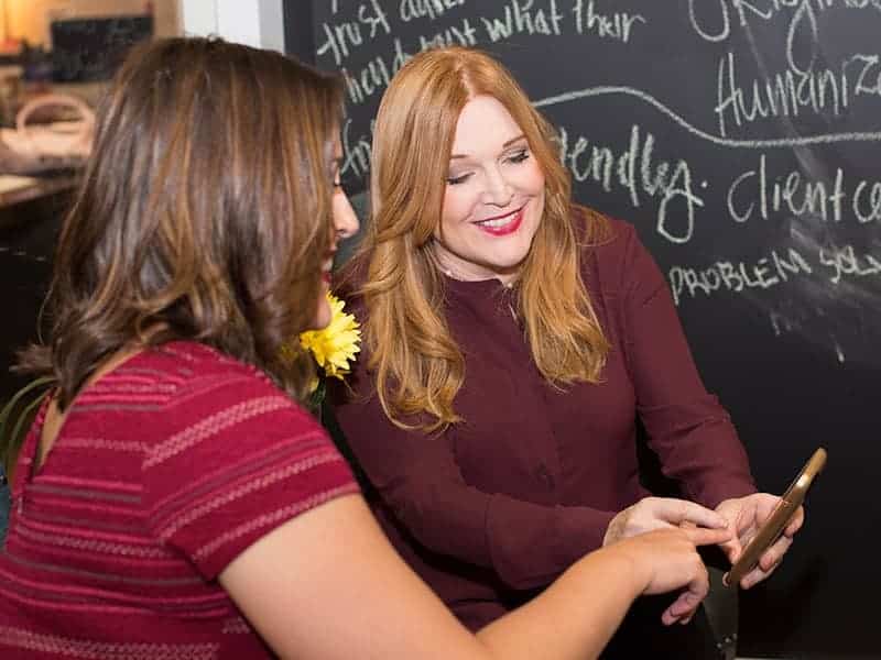 Everywhere Agency founder Danica Kombol speaking with a colleague beside a chalkboard