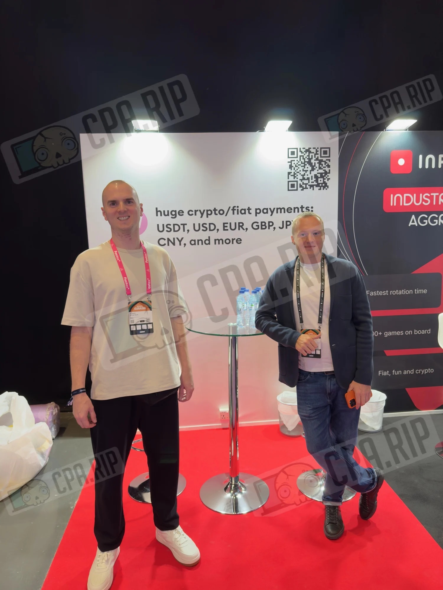 Two attendees at an Evita trade-show display advertising crypto and fiat payments at SiGMA Eurasia 2024