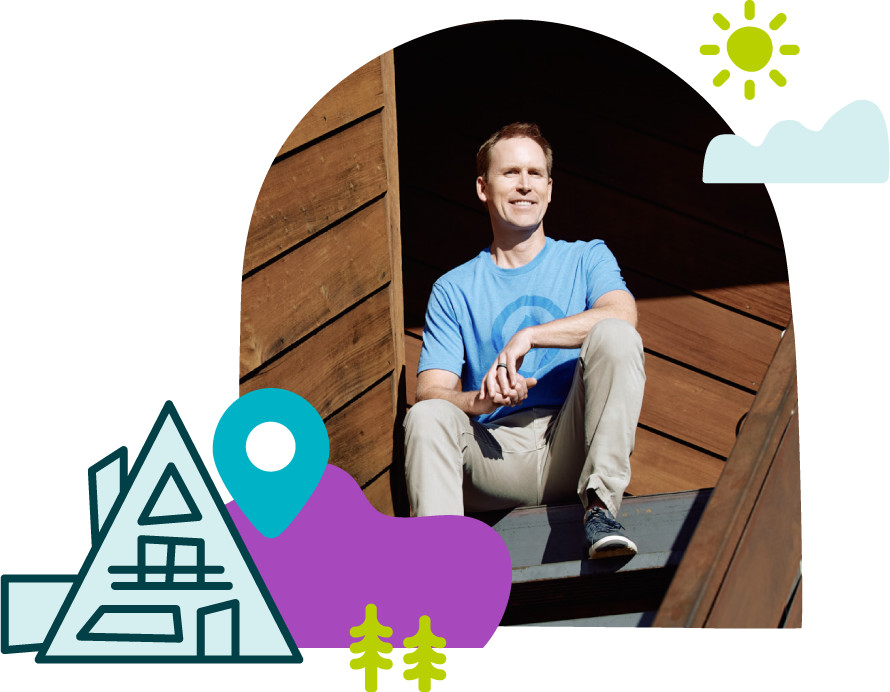 Evolve co-founder Brian Egan seated outside a wooden building, framed by illustrated travel motifs