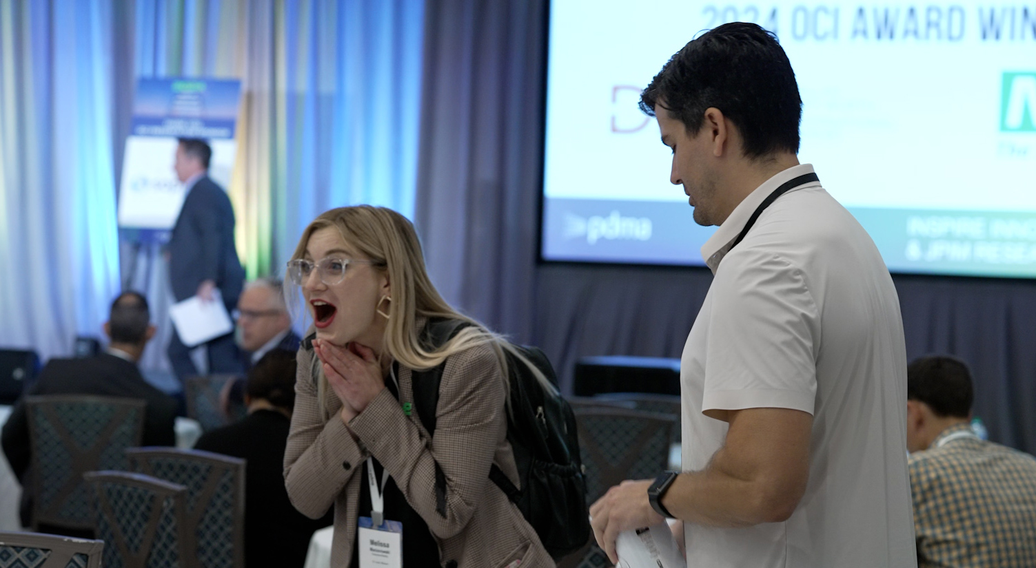 Two attendees speaking on a busy association conference floor