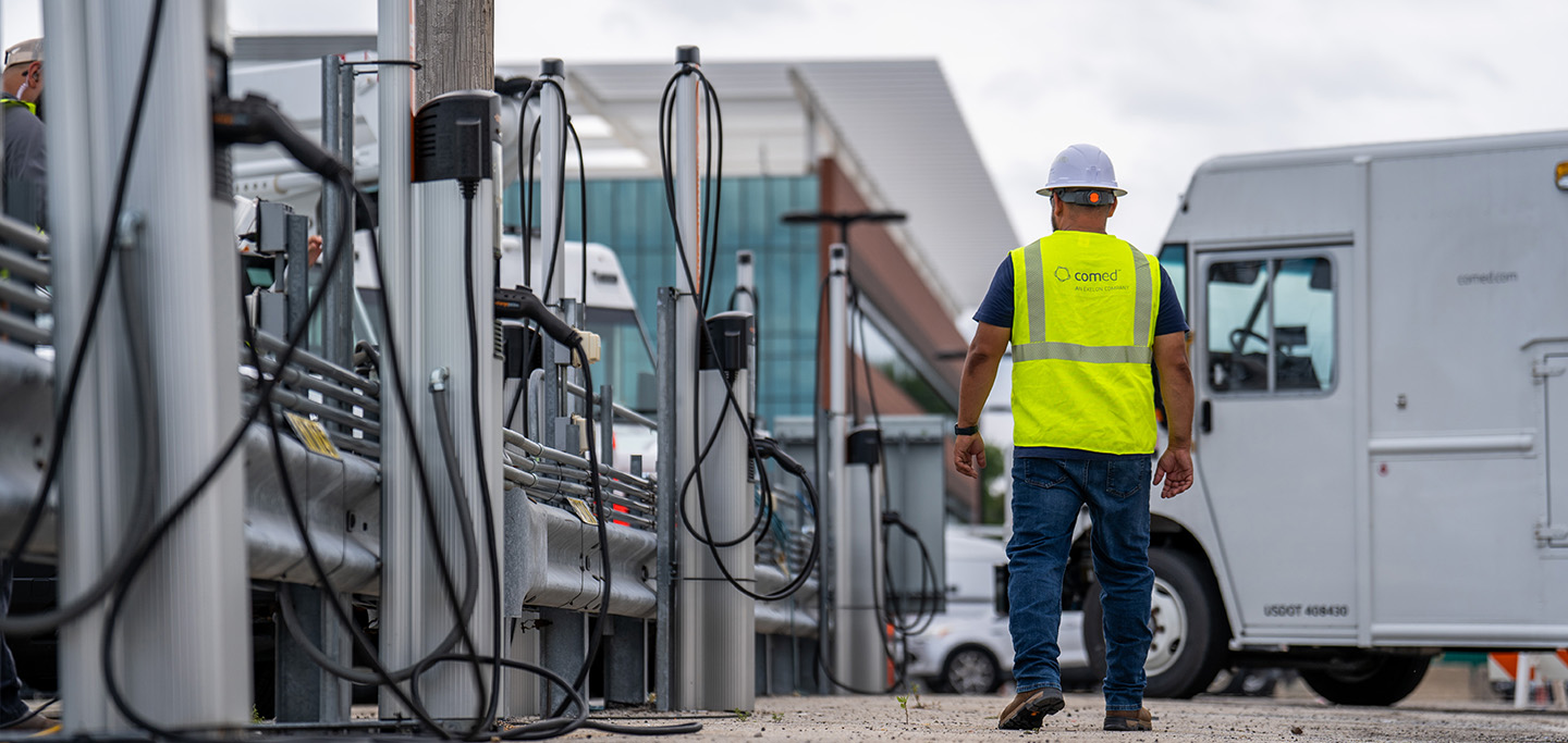 ComEd worker walking beside vehicle charging equipment and utility vehicles