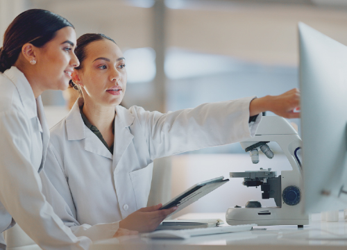 Two researchers in lab coats looking at a computer in Exostar's promotional image