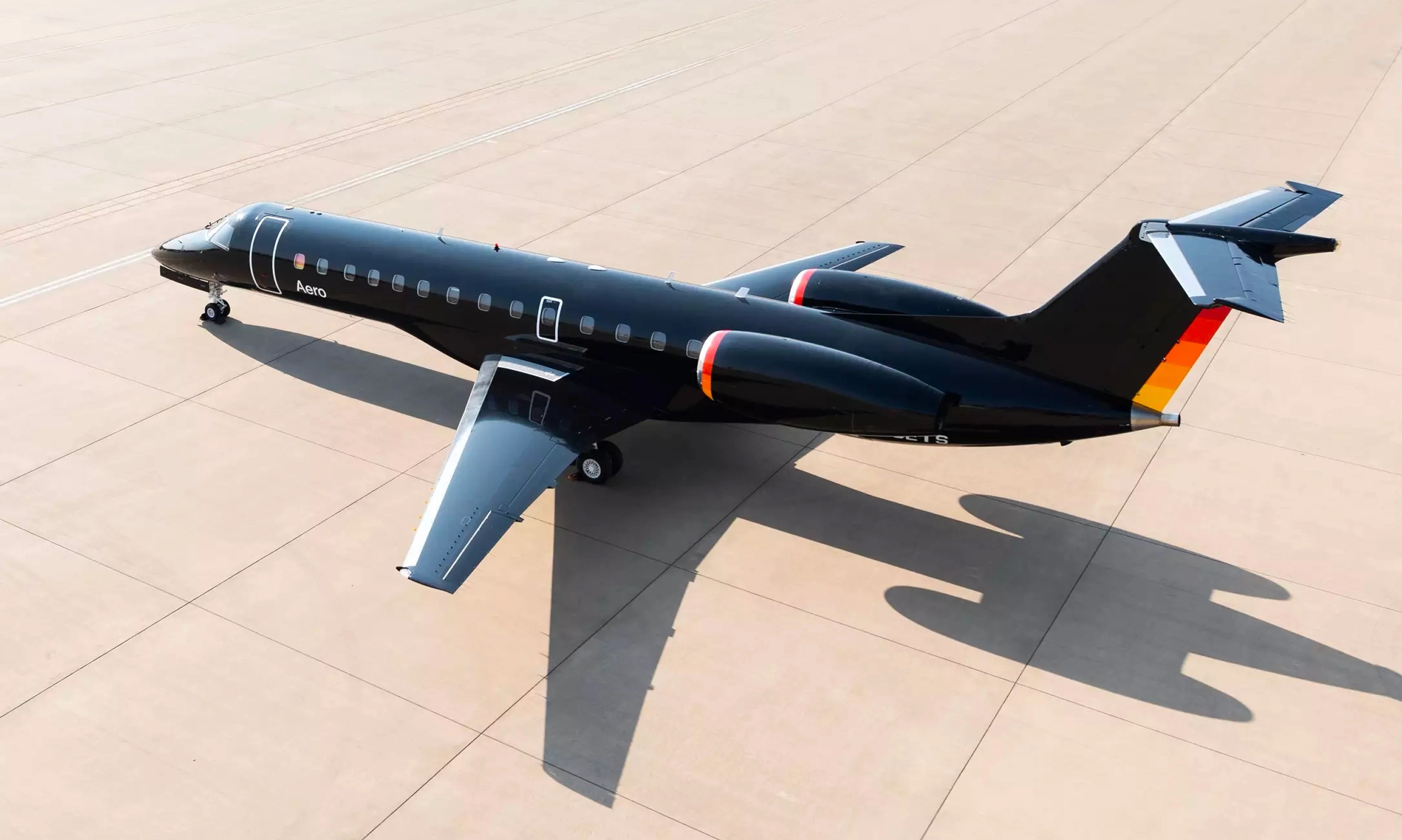 A black Aero passenger jet parked on a sunlit airport apron
