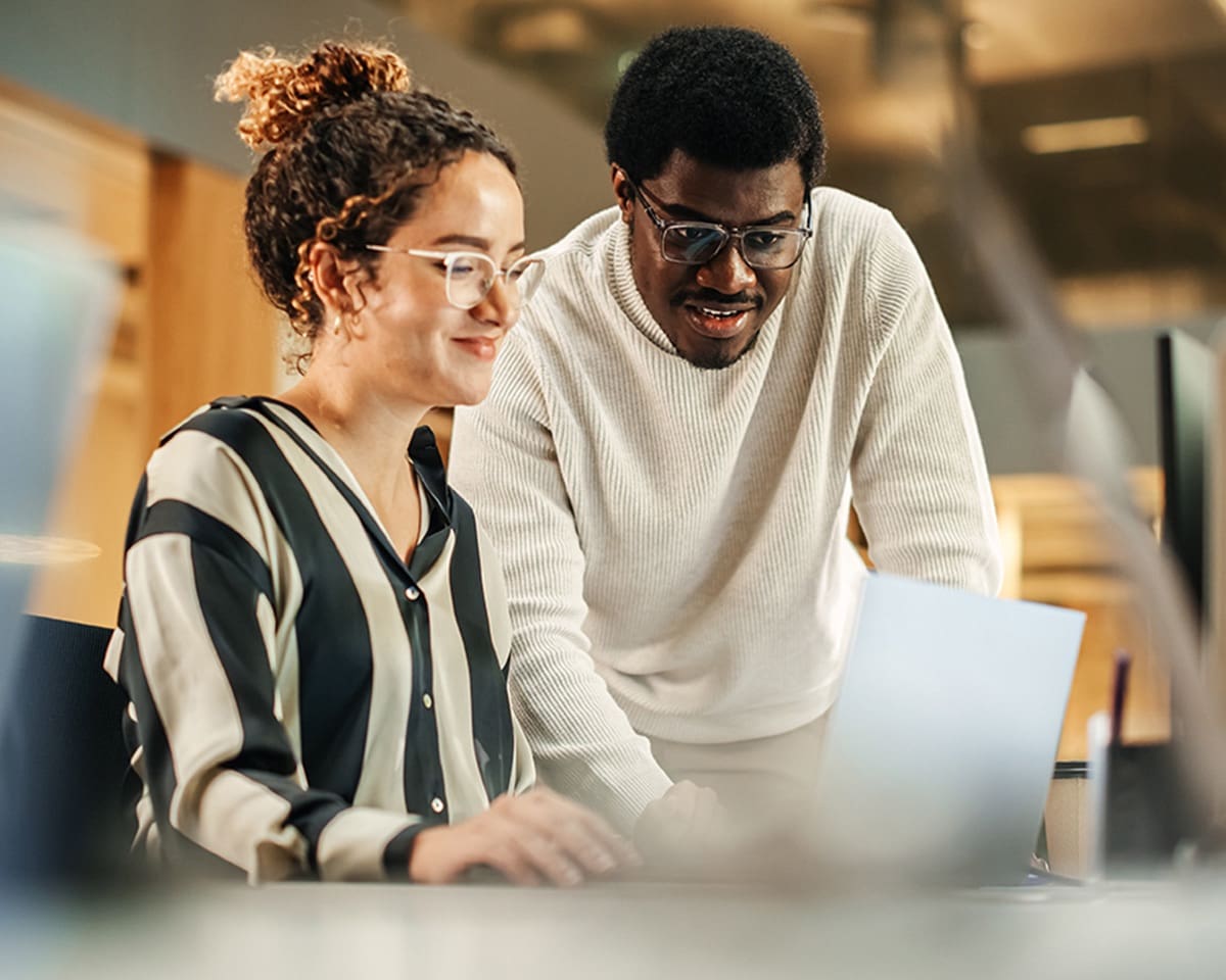 Two colleagues review market information on a laptop