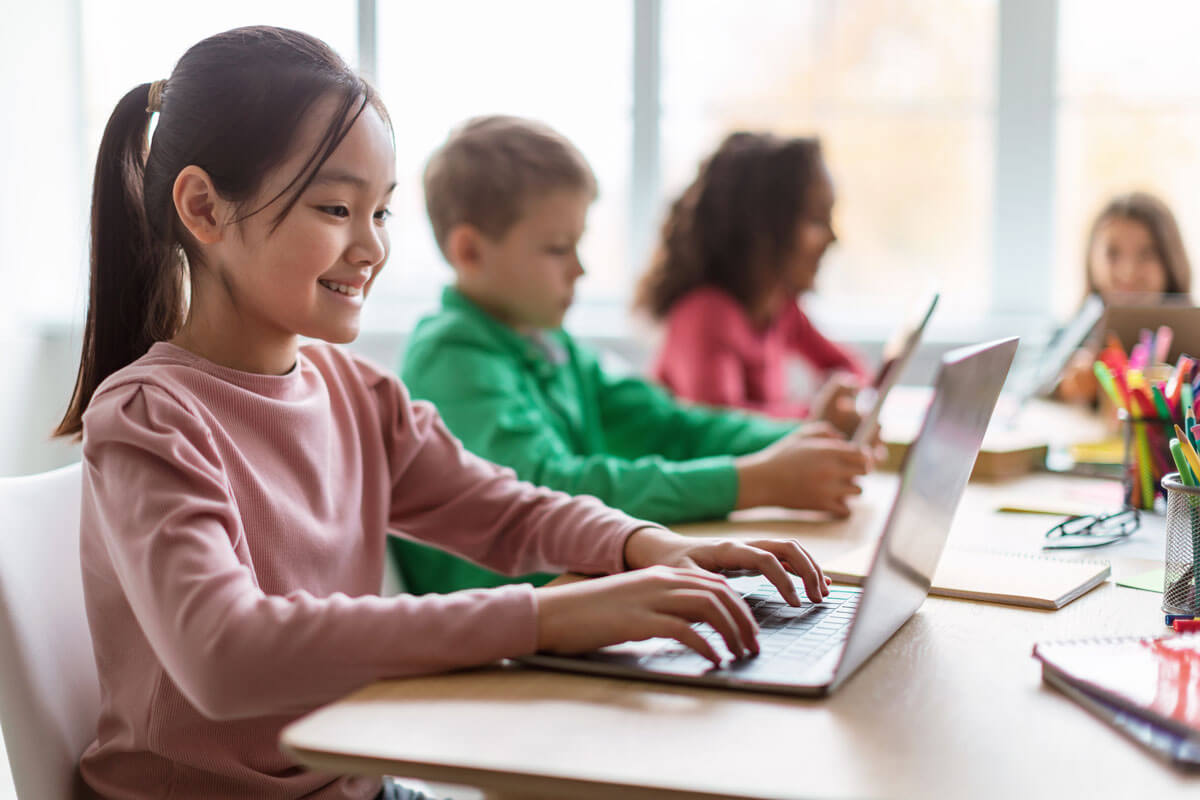 Children working on laptops at classroom desks