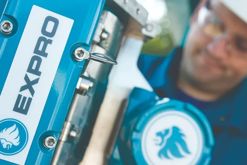 Expro technician working beside teal flow-measurement equipment
