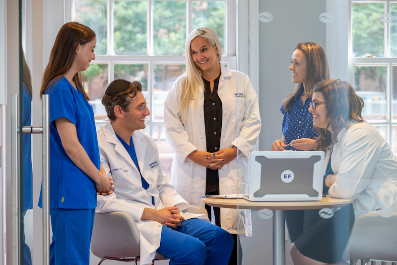 Extend Fertility clinicians gathered around a laptop in a bright consultation room
