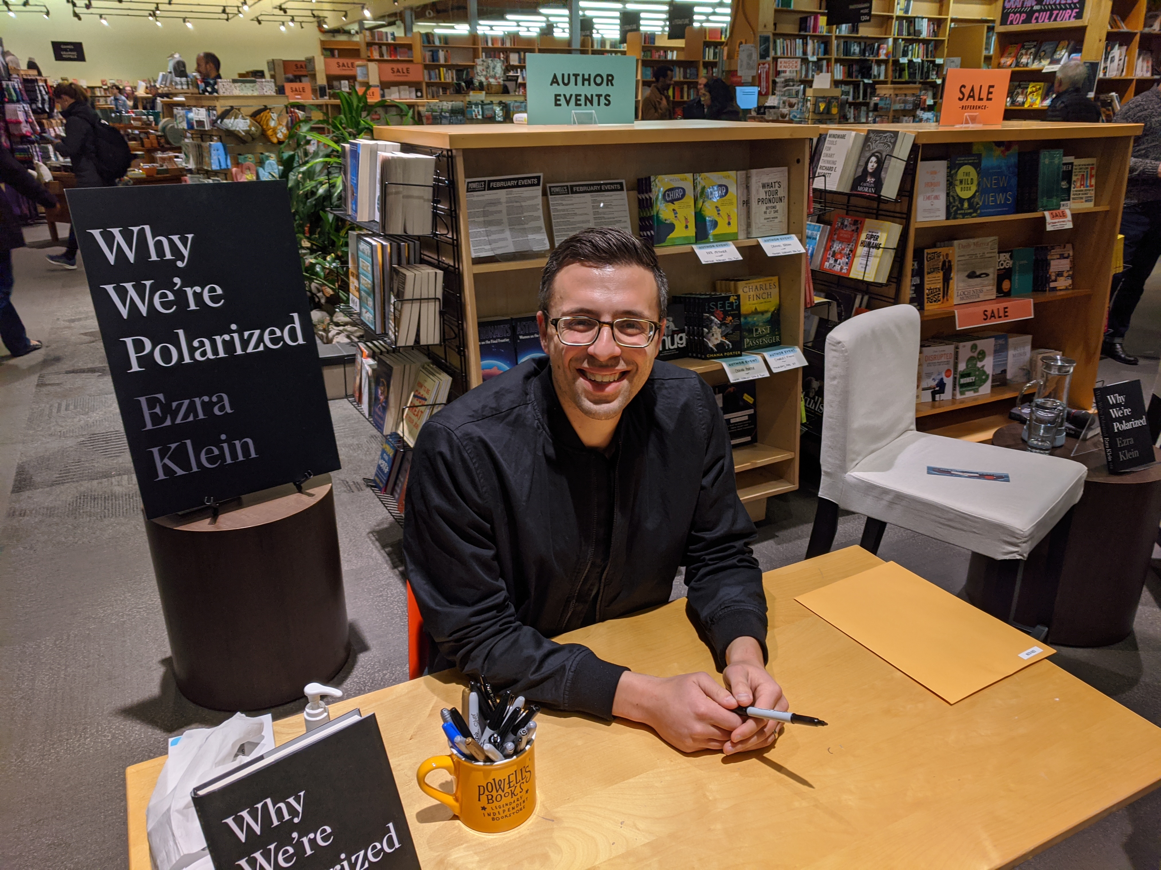 Ezra Klein smiling at a bookstore table during his 2020 Why We're Polarized book tour