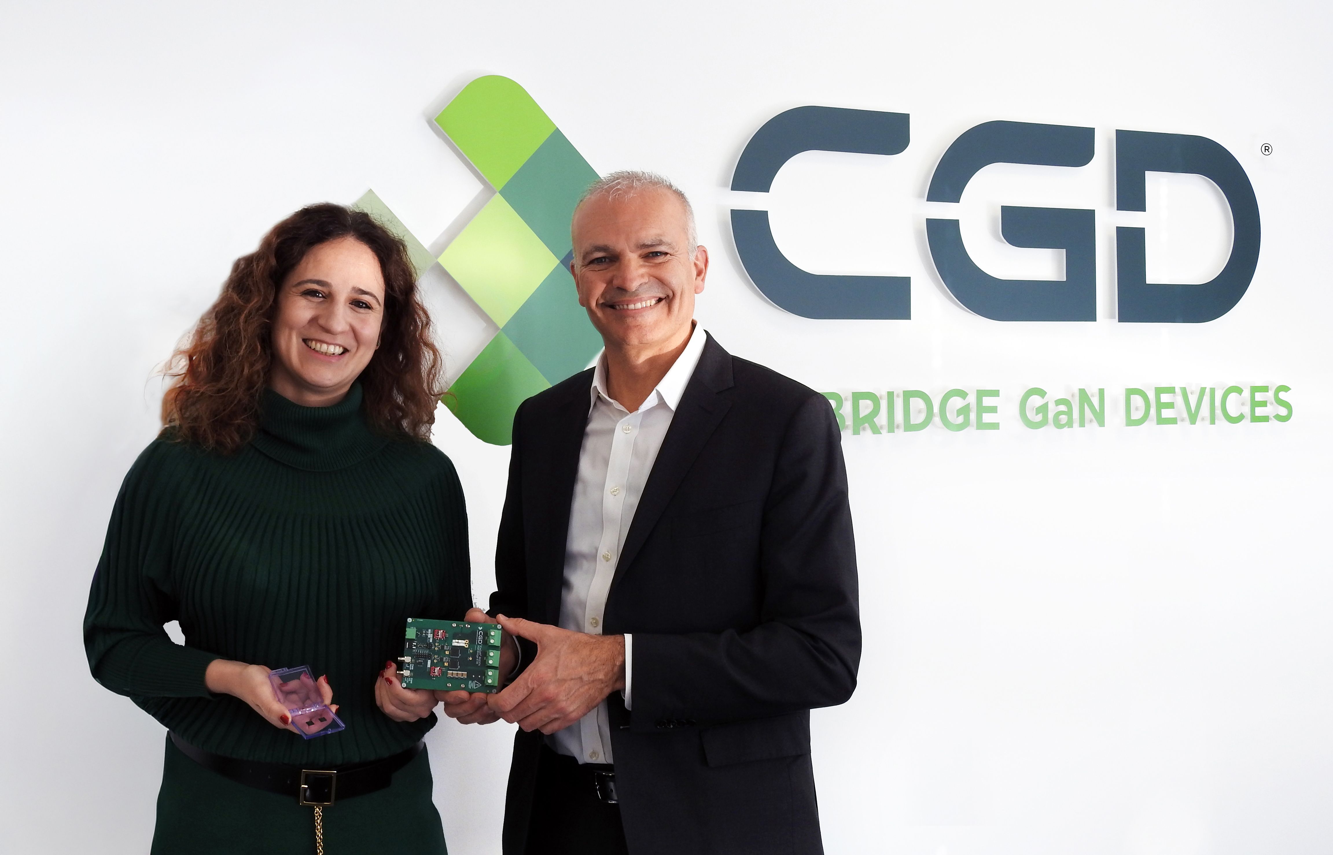Giorgia Longobardi and Fabio Necco stand beneath the Cambridge GaN Devices logo holding circuit boards