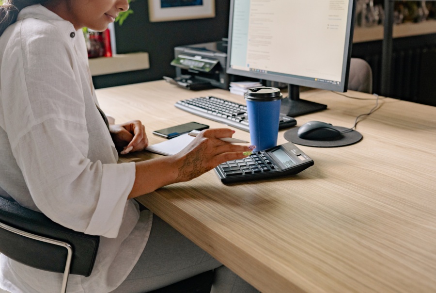 An administrator working with a calculator and computer at a desk