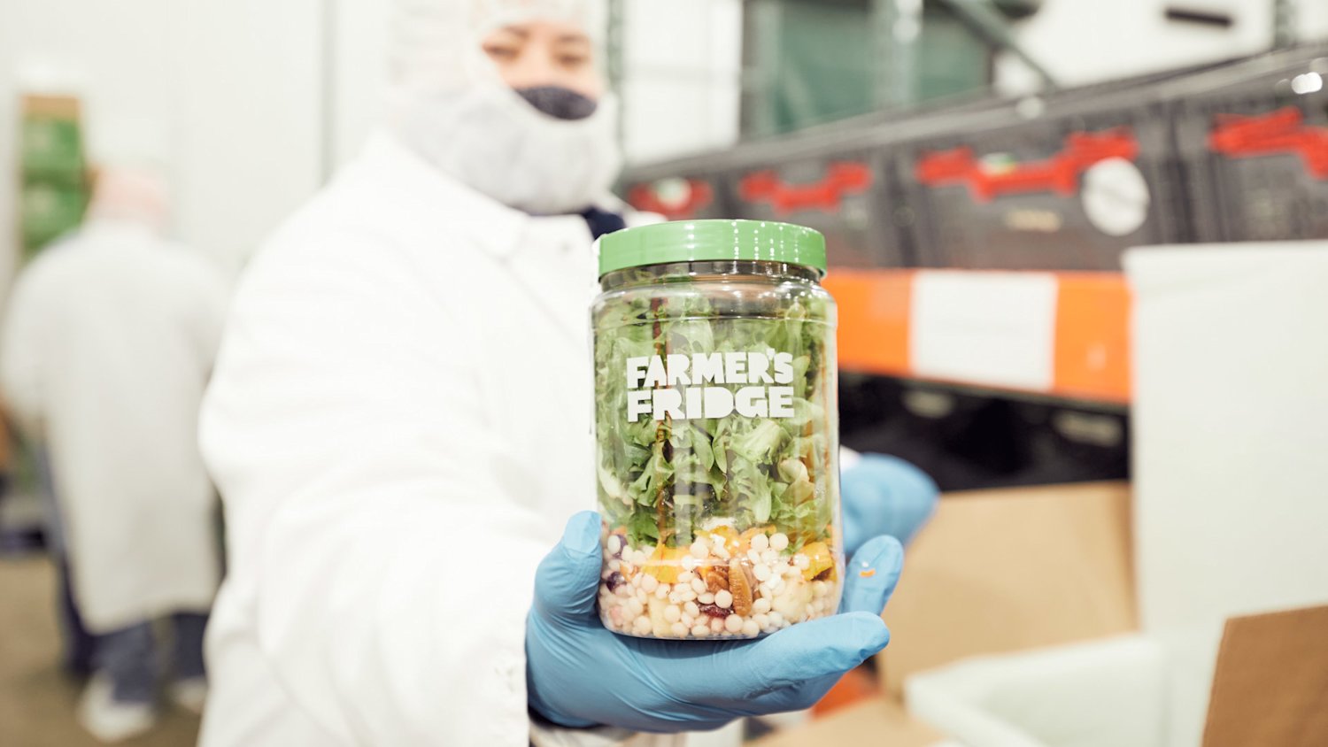 A kitchen employee holds a layered Farmer’s Fridge salad jar