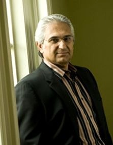 Farsheed Ferdowsi standing beside a window, in the photograph on his author website