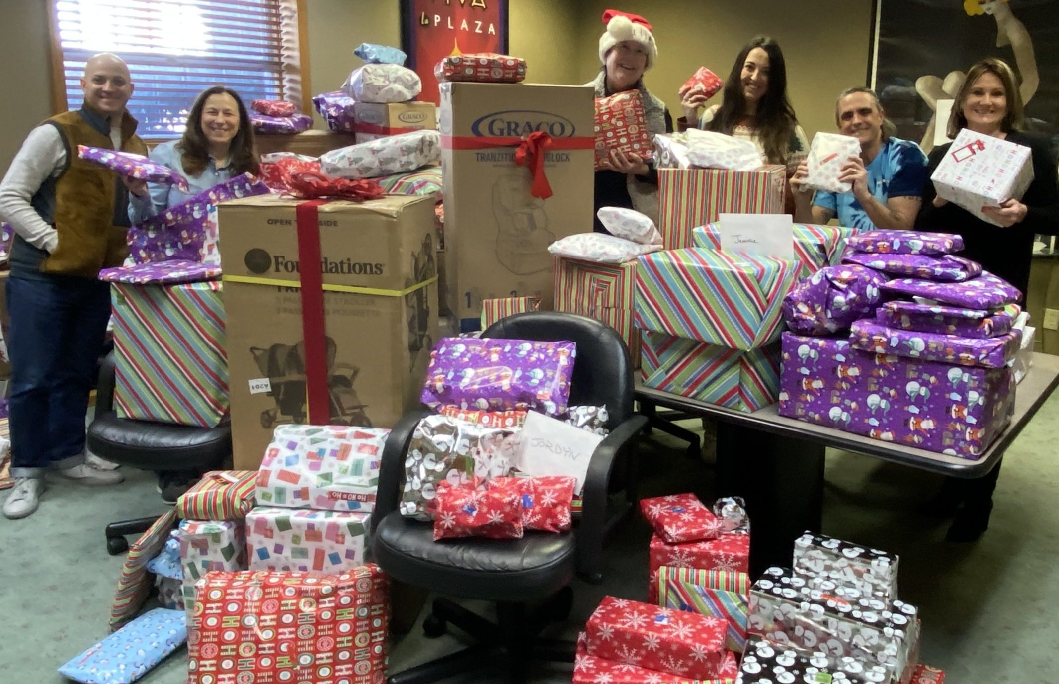 Fasone and Partners team members behind piles of wrapped gifts for Toys for Toddies
