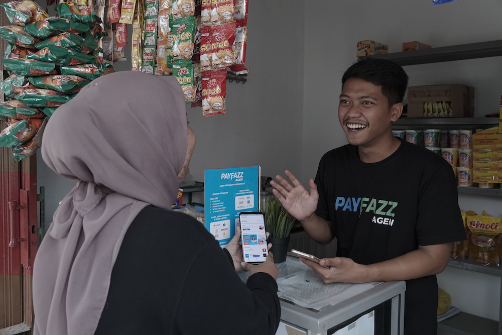 A Payfazz agent talks with a customer at a neighborhood shop