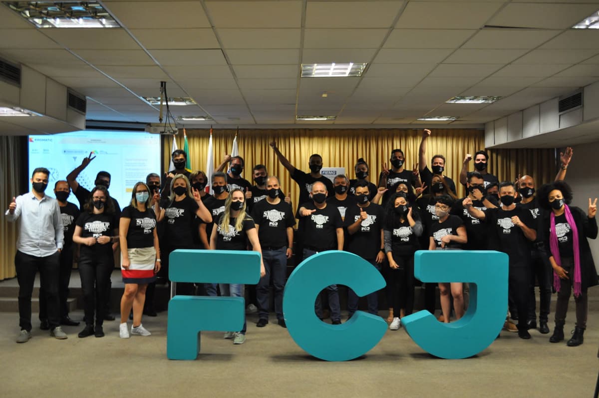 FCJ team and participants gathered behind large turquoise FCJ letters at an immersion event