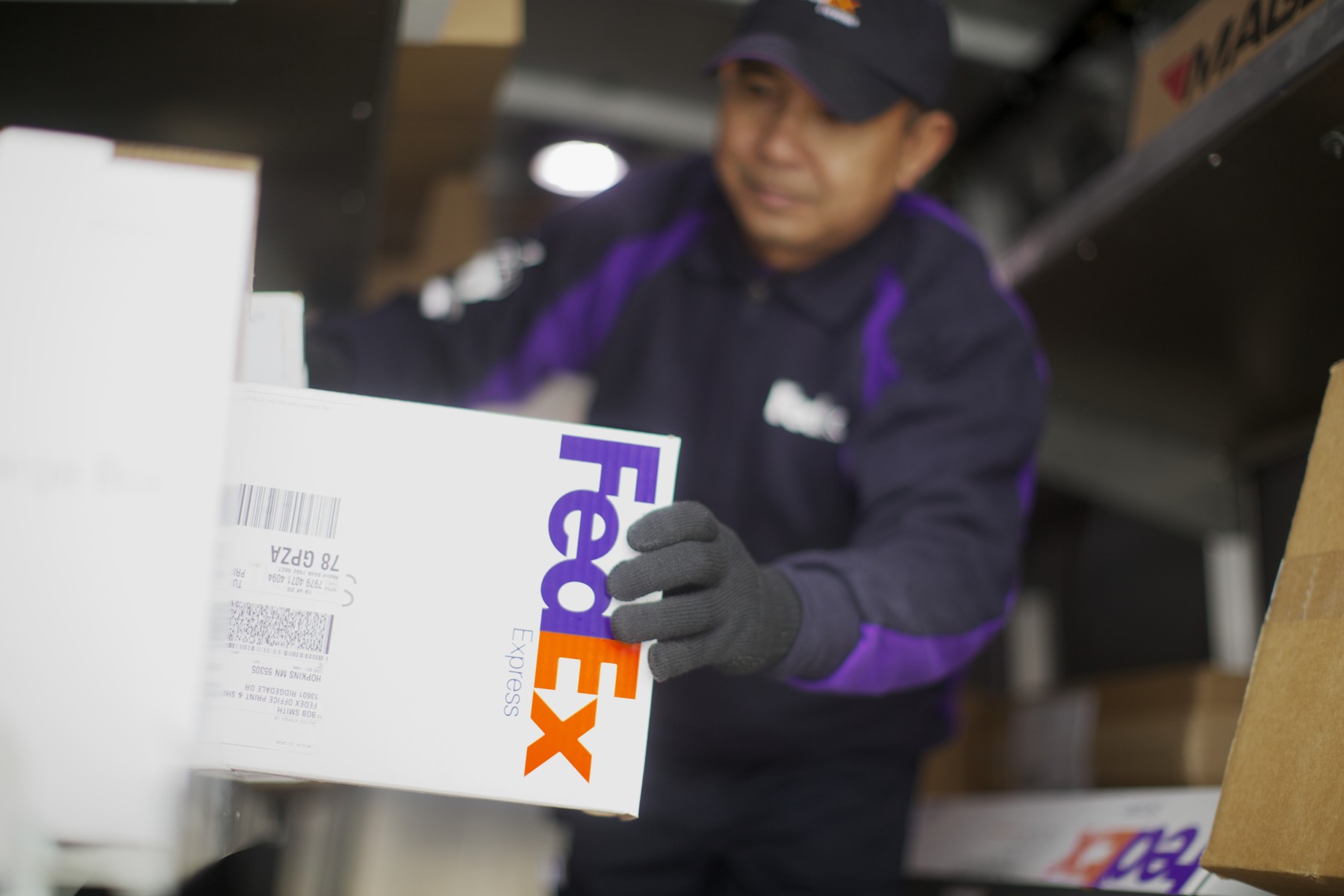 A FedEx courier handling a labeled parcel inside a delivery vehicle