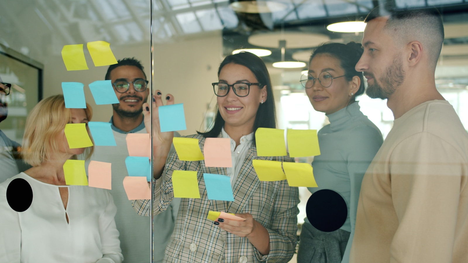 A team collaborating around sticky notes on a glass wall