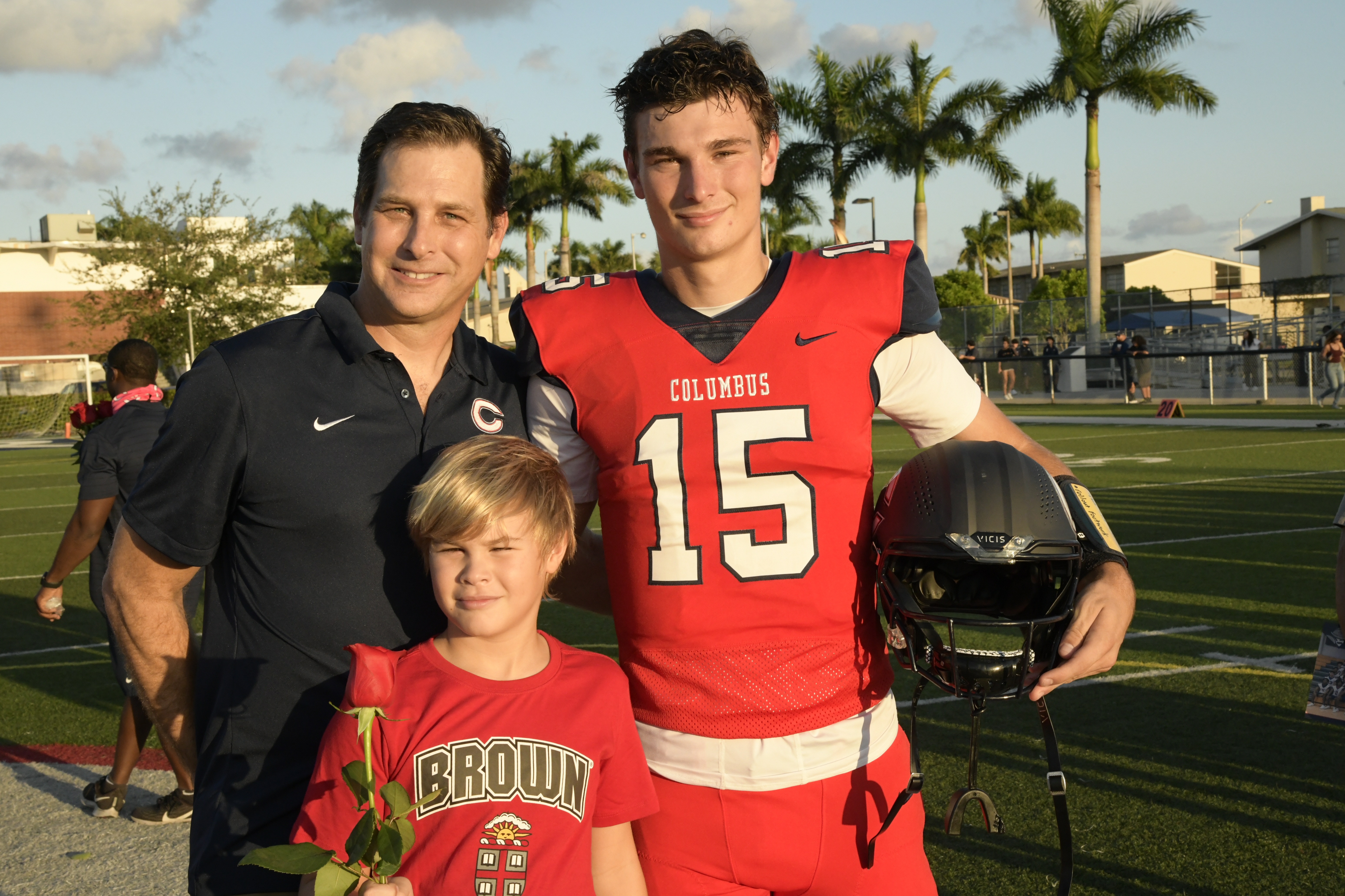 Fernando G. Mendoza with his son Fernando in a Columbus number 15 football jersey and his younger son on the school field