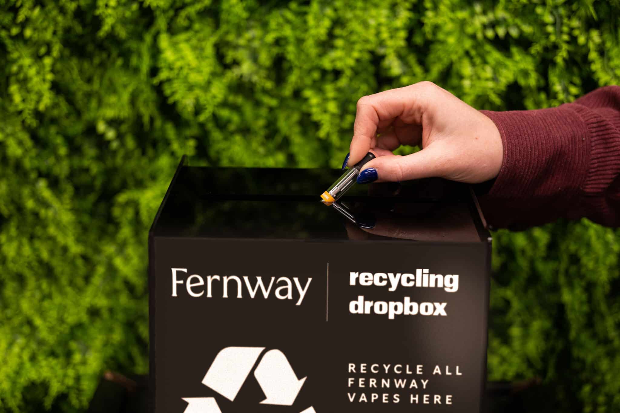 A used Fernway cartridge being placed into a black recycling dropbox