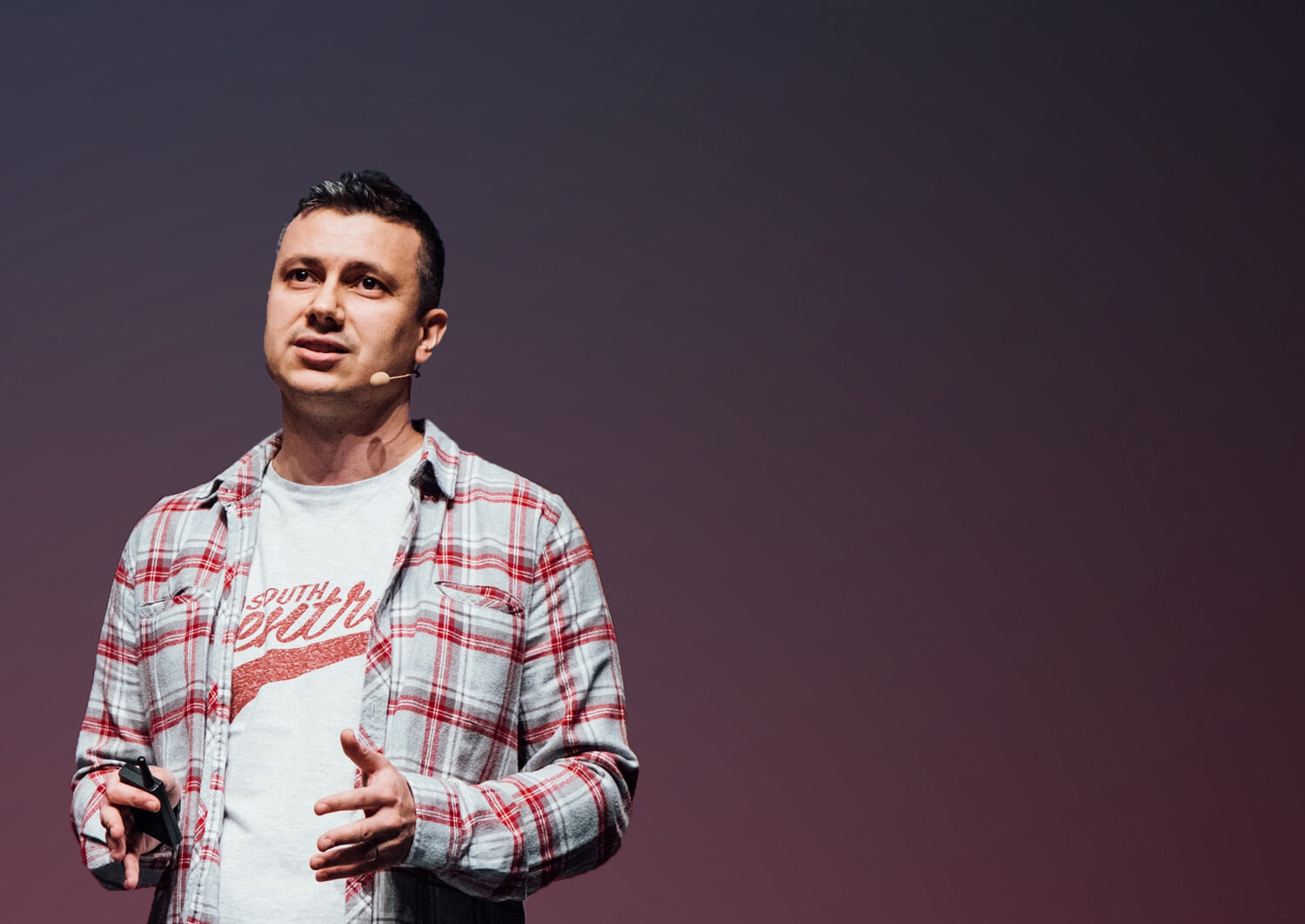 Ferruh Mavituna speaking onstage, wearing a headset microphone and holding a presentation remote