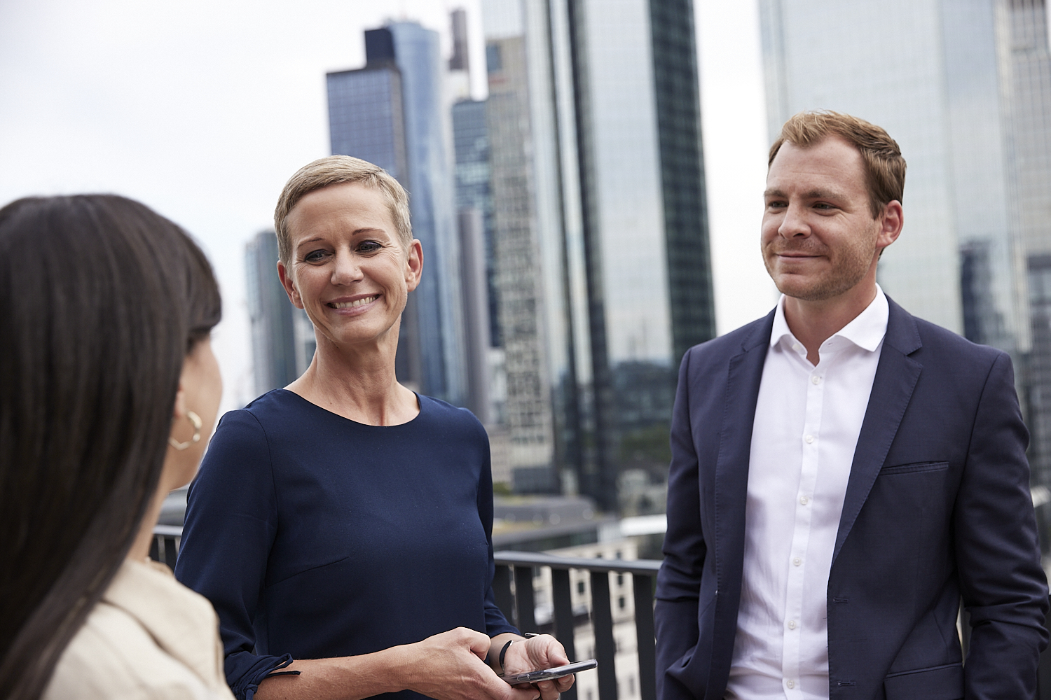 FGS Global colleagues speaking on a terrace with Frankfurt office towers behind them