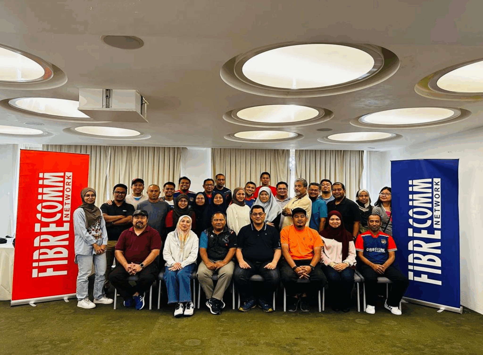Fibrecomm participants gathered between company banners at the January 2025 business-planning retreat