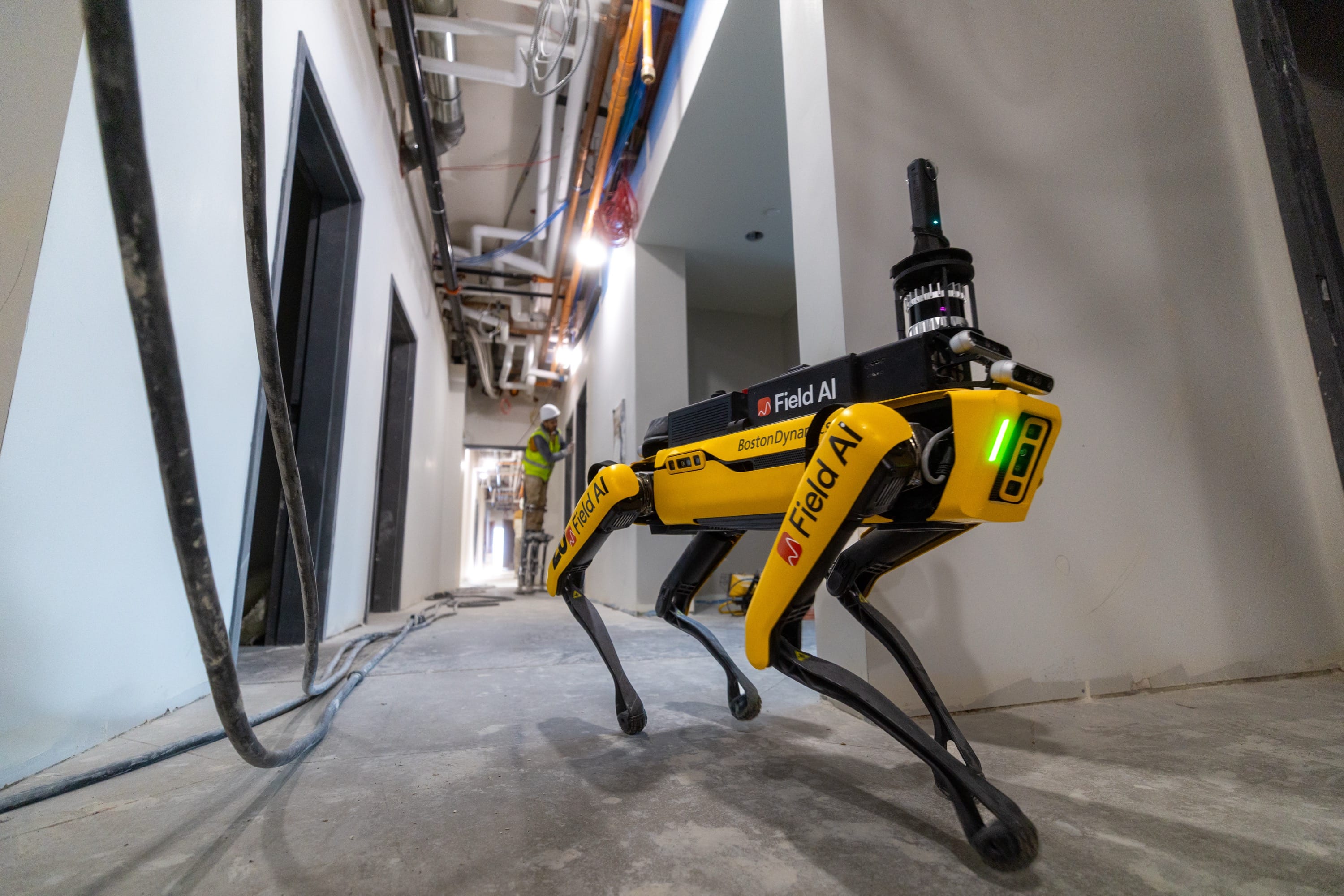 Boston Dynamics Spot carrying FieldAI sensors in an unfinished construction corridor