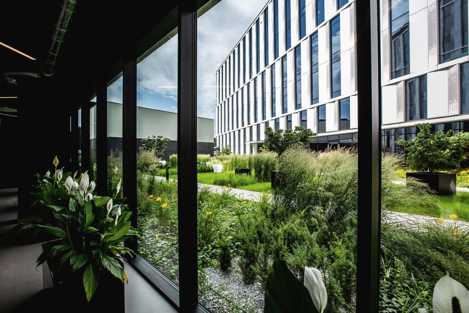 Glass-fronted office courtyard with planted gardens, pictured in Findev’s Poland careers section