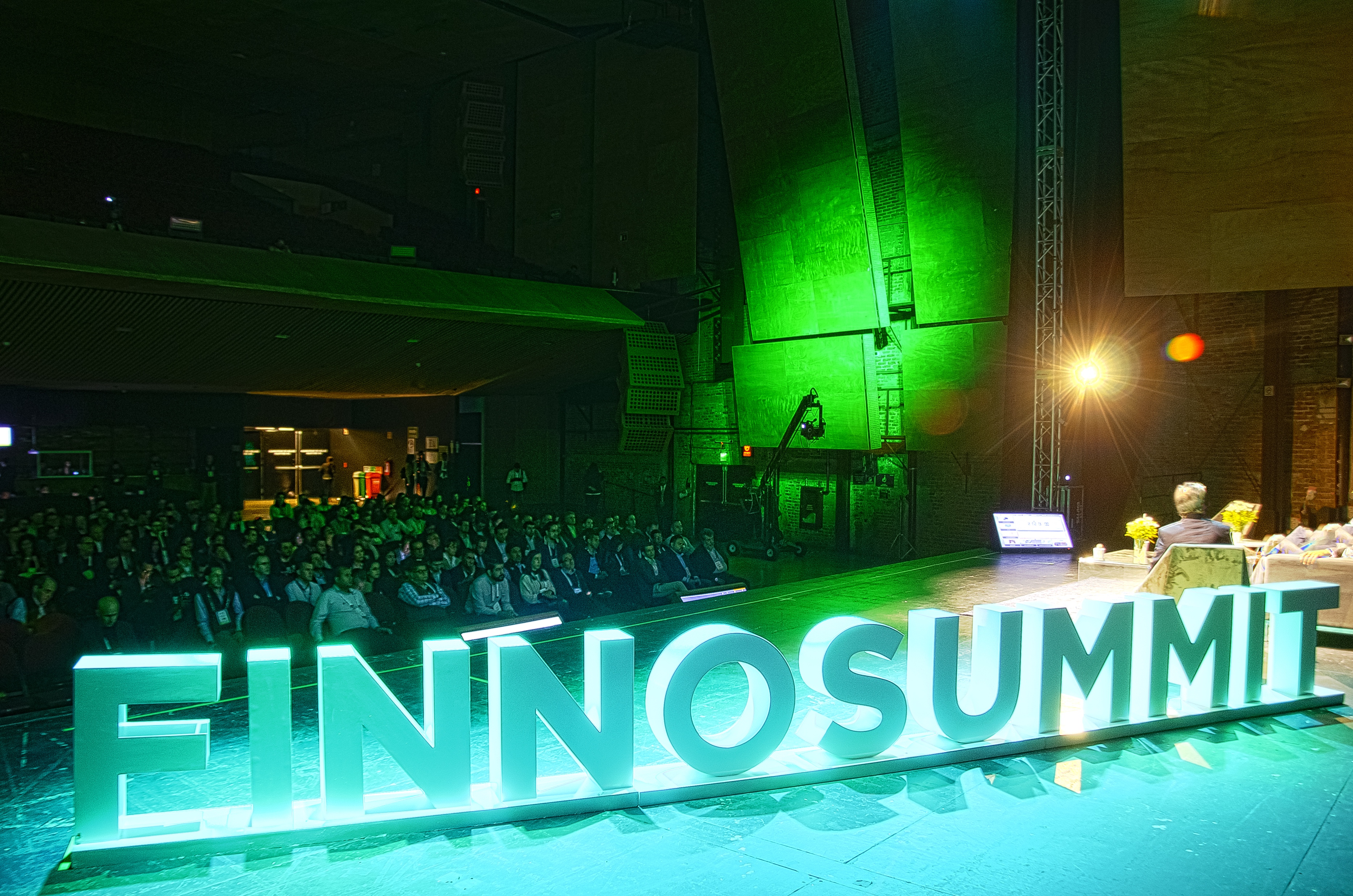 A speaker on an illuminated FINNOSUMMIT conference stage