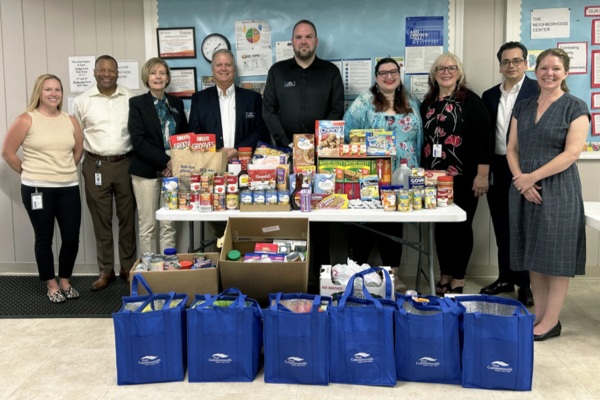 First Commonwealth and neighborhood center representatives stand behind donated food and blue bags
