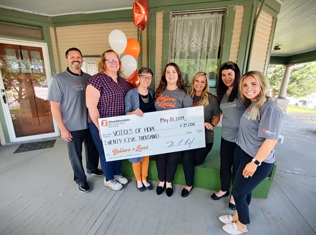 A group holding a First Interstate Foundation check for $25,000 payable to Voices of Hope, dated May 20, 2024