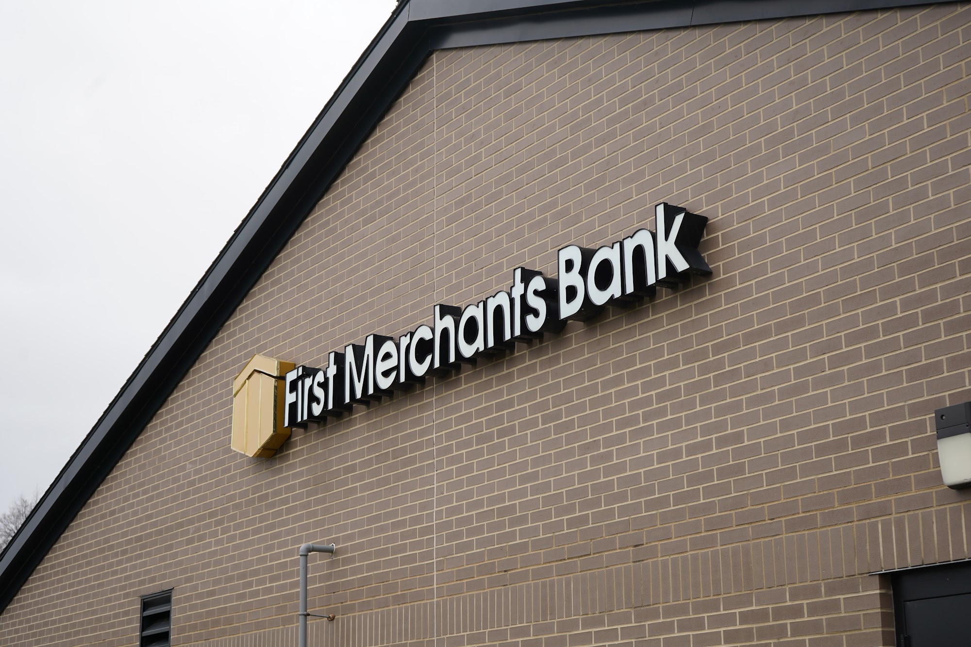 First Merchants Bank lettering and gold shield on the brick exterior of its North Nebo Road branch in Muncie