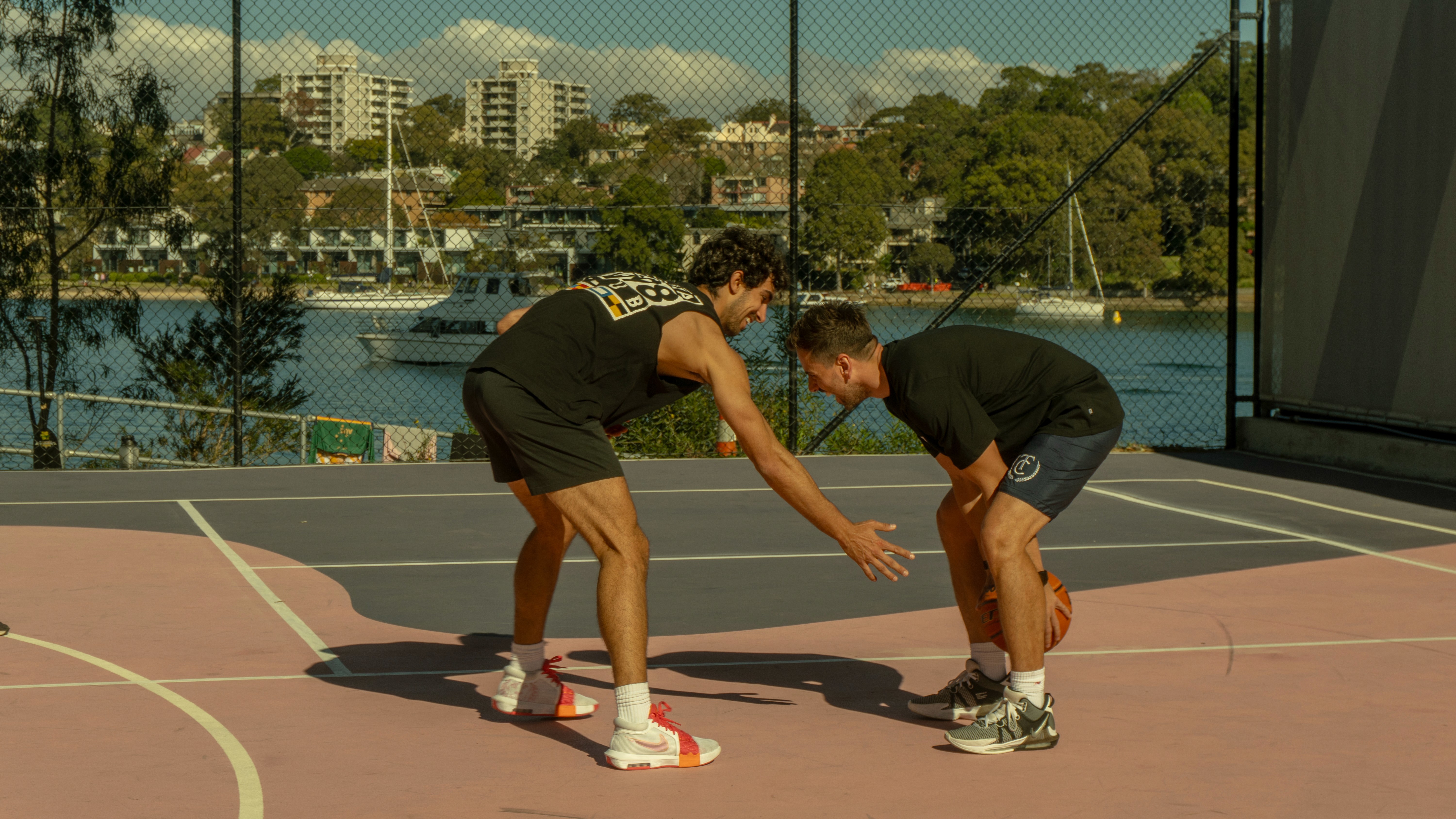 Two people playing basketball on an outdoor court in a Fishburners website photograph