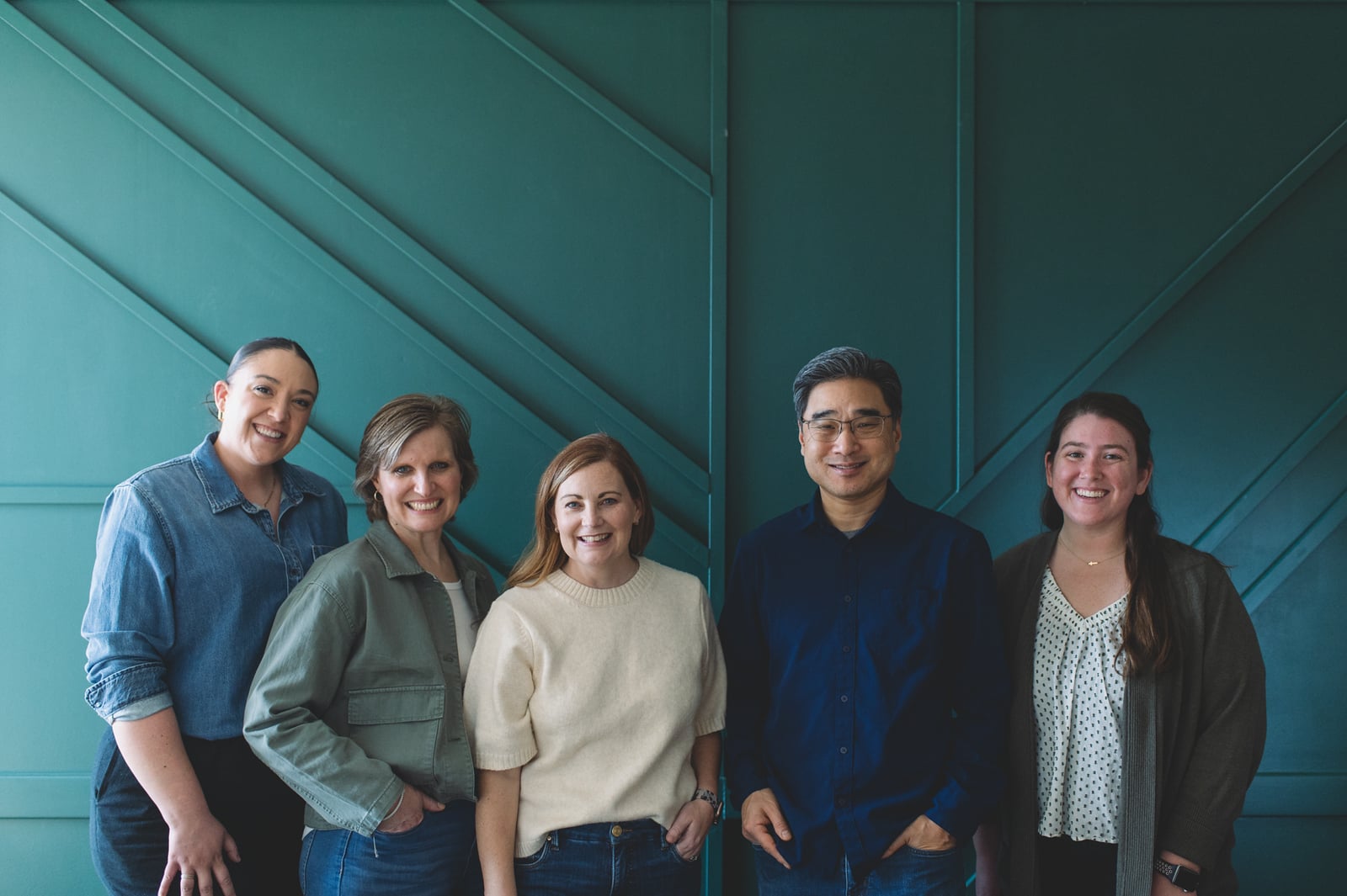 Five members of the Fishhook team standing against a teal paneled wall