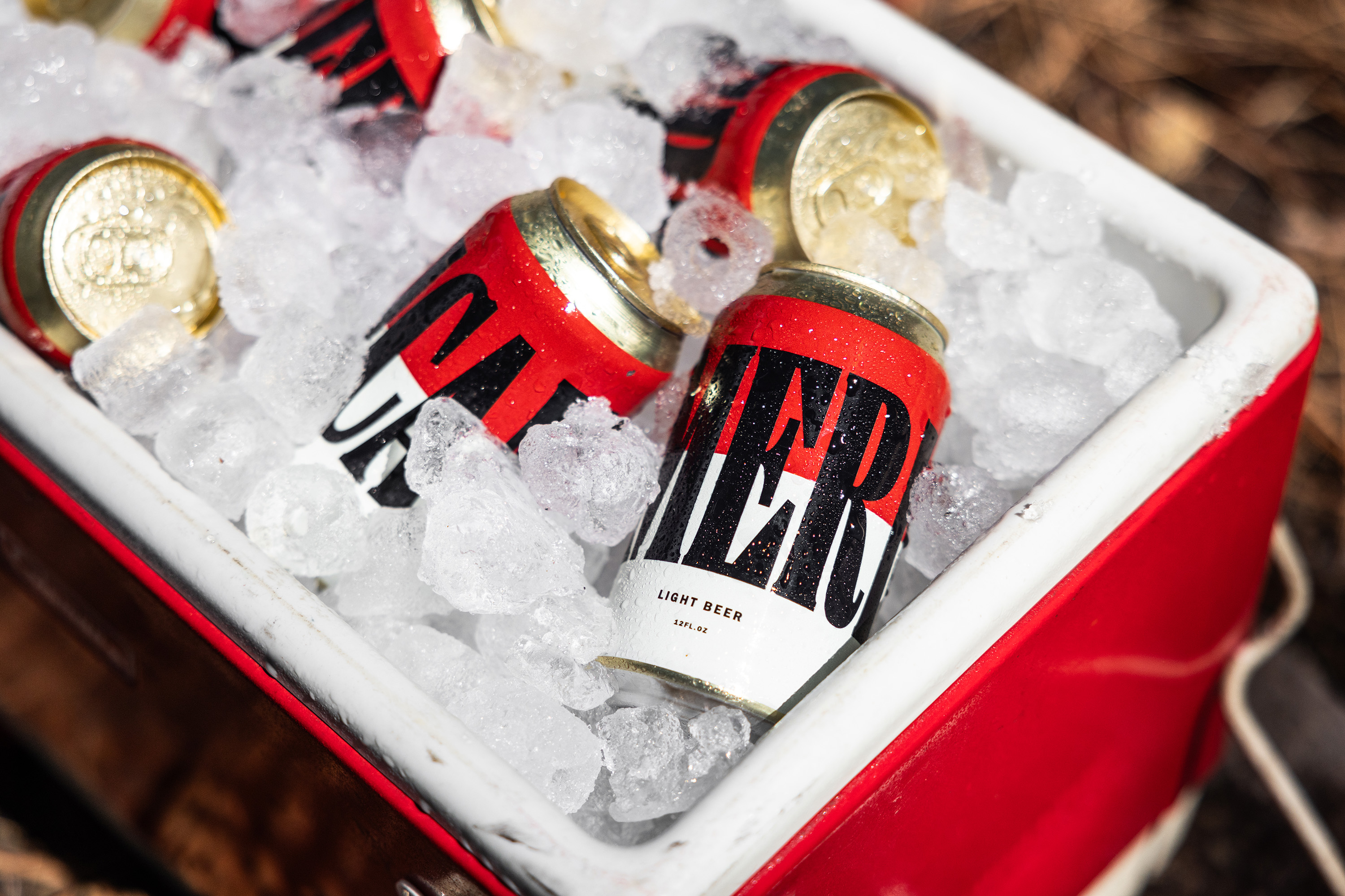 MERICAN beer cans nestled in ice inside a red cooler