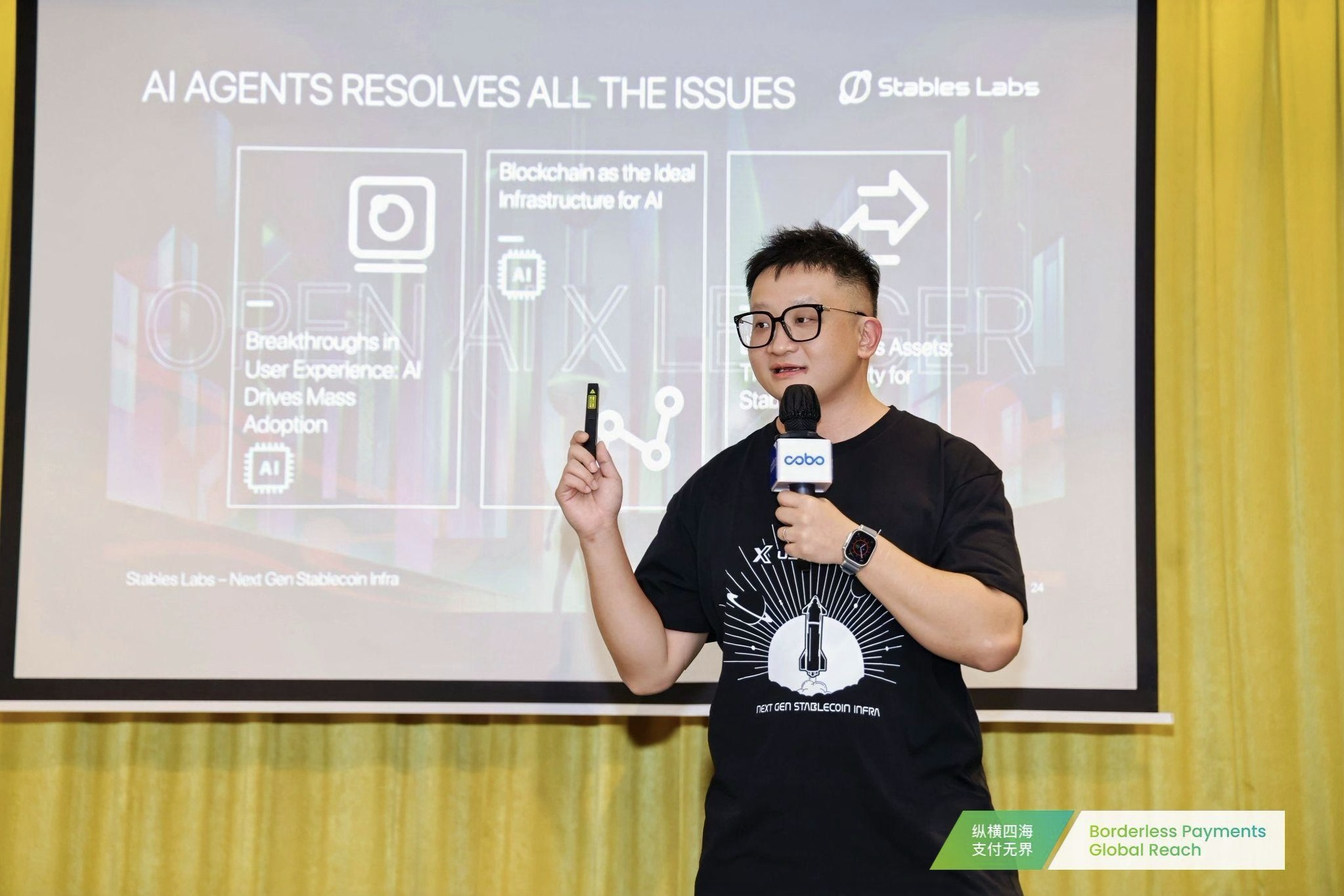 Flex Yang holding a microphone and presentation remote at a Stables Labs payments event in Hong Kong