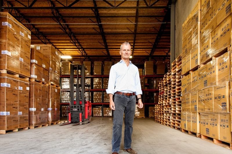 Flexe co-founder Karl Siebrecht standing between pallets of boxed goods in a warehouse
