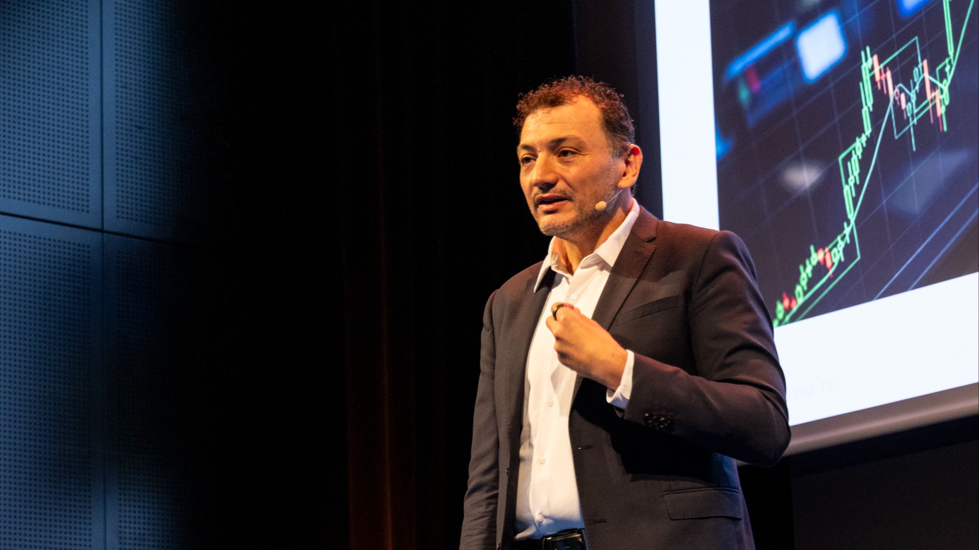 Florian Douetteau speaking onstage beside a projected line chart