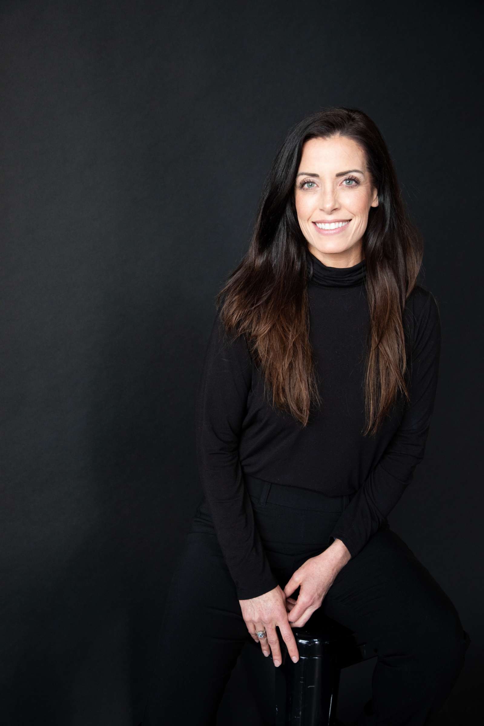 Flourish founder and CEO Megan Nivens-Tannett seated against a dark studio background