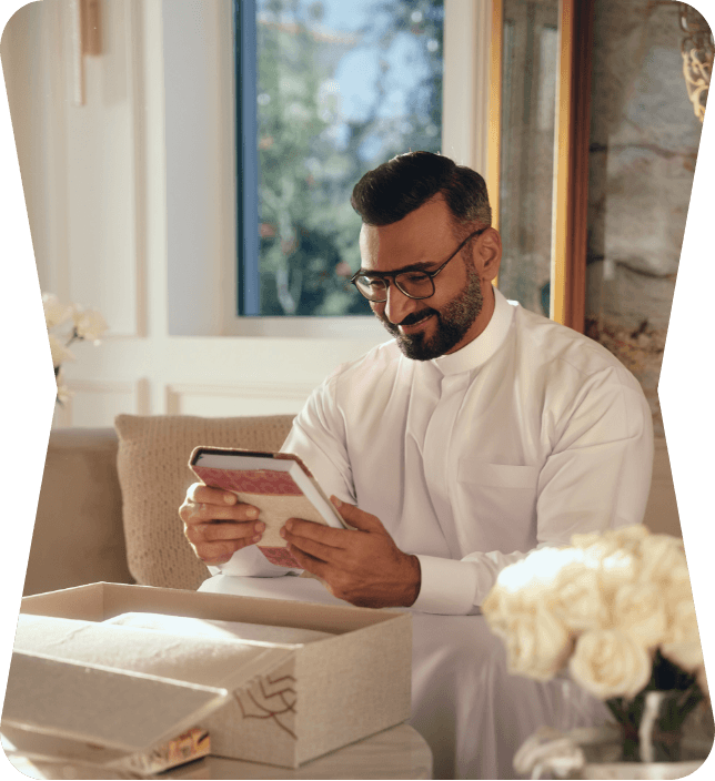 Floward campaign photograph of a man opening a gift beside white flowers