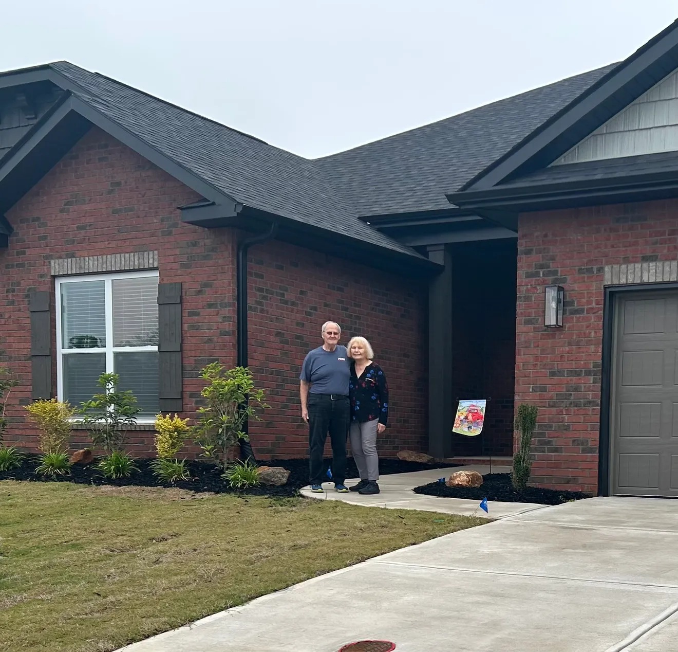 Two homeowners standing outside a brick house in a Flyhomes customer photograph