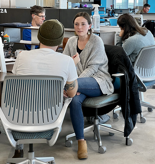 People working and talking among the desks at Flywheel Winston-Salem