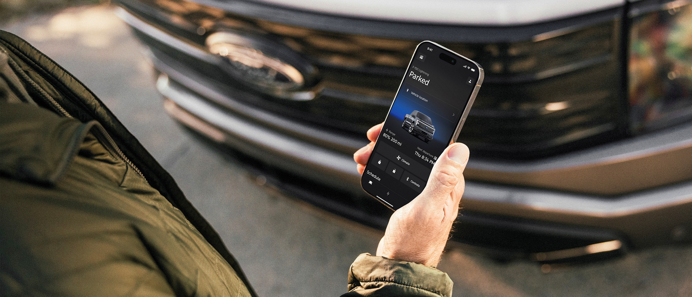 A Ford owner uses a smartphone beside an F-150 Lightning