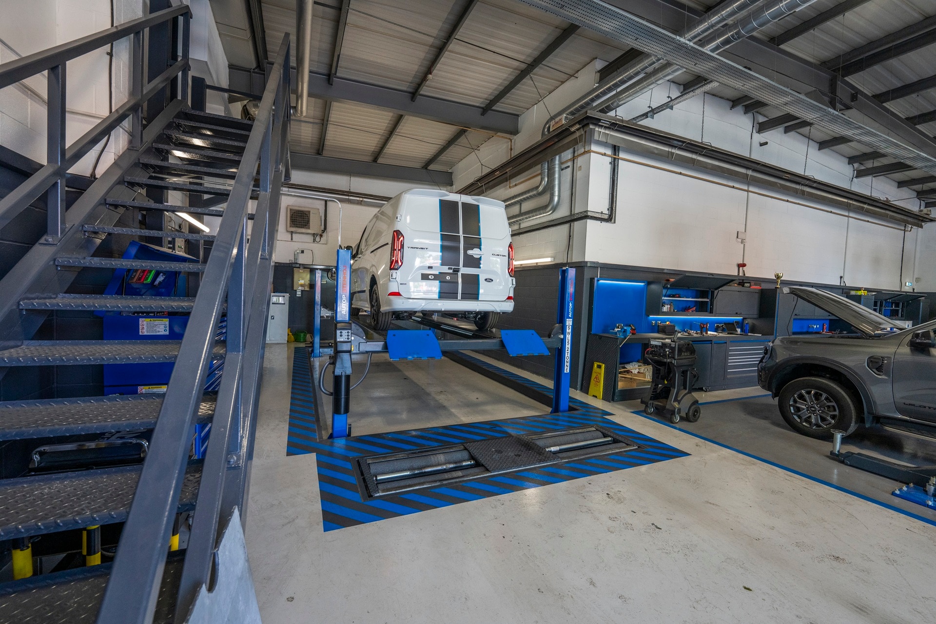 Ford Transit Custom raised on ramps in a commercial vehicle workshop
