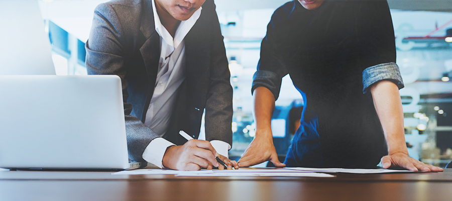 Two people reviewing paperwork together at an office table