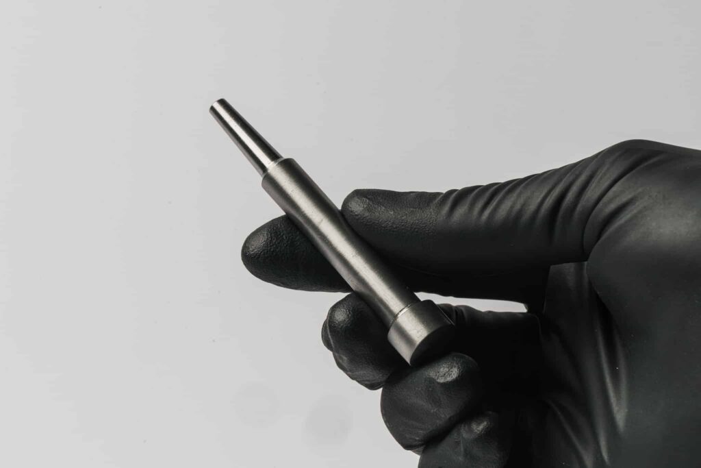 A gloved hand holds a machined metal part made by Foundation Alloy