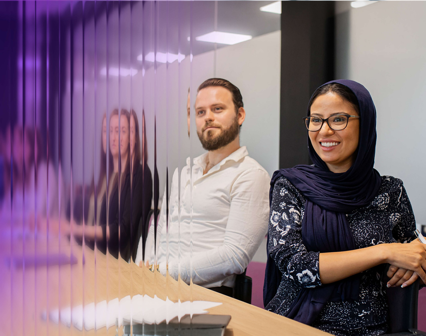 FourNet colleagues in a meeting room beside a rippled purple glass wall